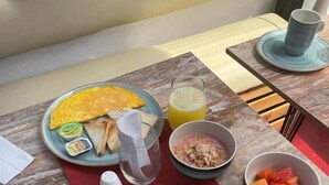 A breakfast table with plates of eggs, toast, and fruit, along with a glass of orange juice. - Candilejo Hotel Boutique (Cartagena)