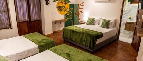 A hotel room with two beds, a green and white color scheme, a wall decoration, and a bathroom visible through an open door.
