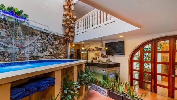 A spa area with a hot tub, a stone wall, and a wooden staircase. - Candilejo Hotel Boutique (Cartagena)