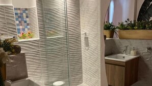 A modern bathroom with a glass shower enclosure, a sink, and a small vanity. - Candilejo Hotel Boutique (Cartagena)