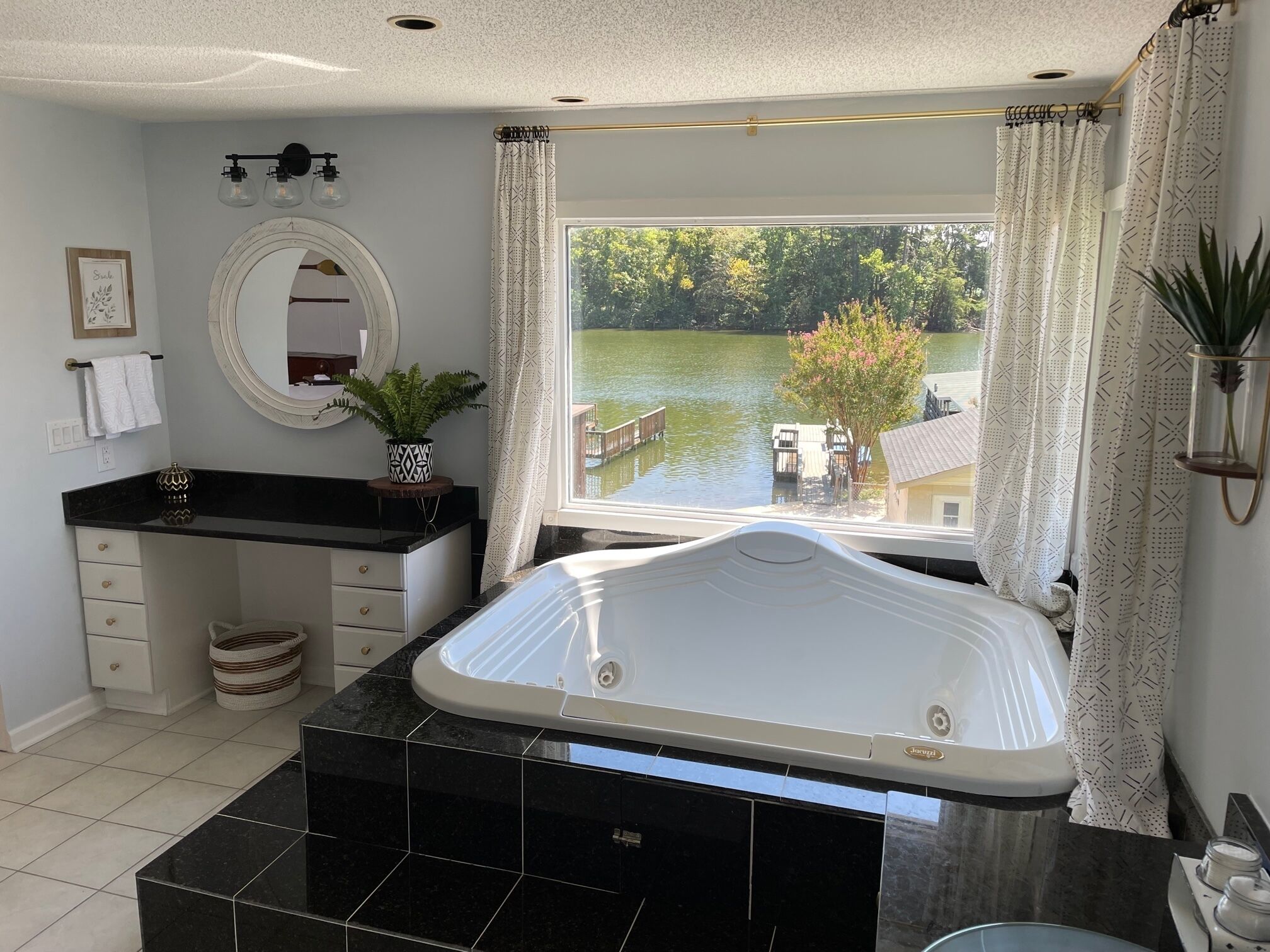 A bathroom with a bathtub, a sink, a mirror, and a window with a view of a lake.