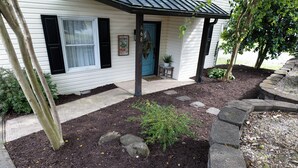 Une maison avec un porche à l’avant, une porte bleue et une pancarte indiquant « Bienvenue ».