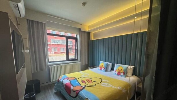 A hotel room with a large bed, a window with curtains, a radiator, and a wall-mounted air conditioner. - Piaohome Chain Hotel (Beijing Guomao Dawang Road Subway Station Store) (Beijing)