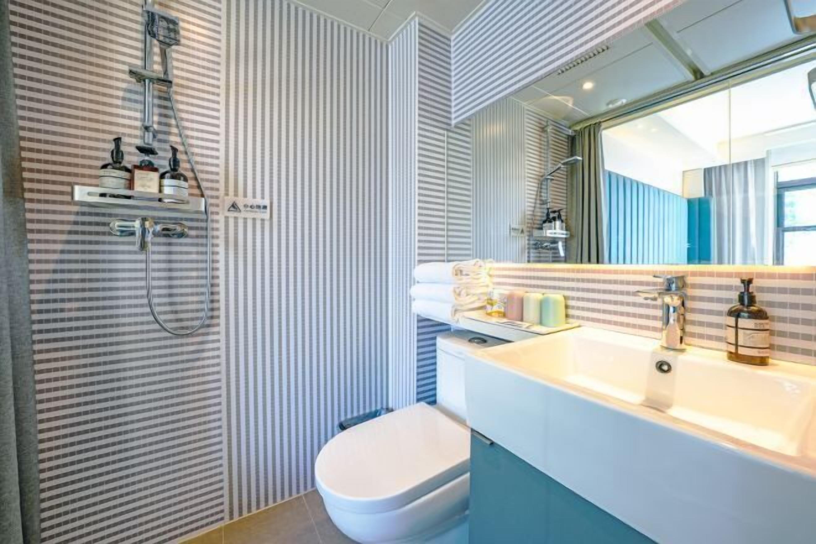 A modern bathroom with a shower, toilet, and sink.