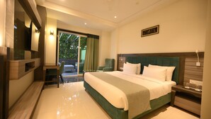 A modern hotel room with a large bed, a desk, and a seating area. - The Hotel Mudra (Varanasi)