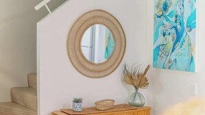 A staircase with a round mirror above a wooden console table, a vase with dried plants, and a painting on the wall. - Unit 94 - Modern and Stylish 2 Bedroom Townhouse in Resort (Noosaville)