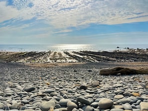 A rocky beach with a clear sky and the ocean in the background.
