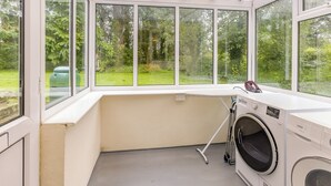 A laundry room with a large window, a washing machine, and a drying rack. - Pine Cottage - UK46874 (Hartland)