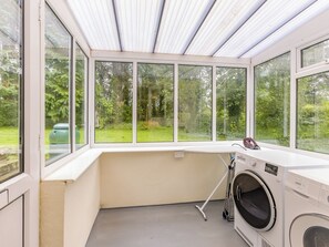 A laundry room with a large window, a washing machine, and a drying rack.