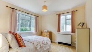 A bedroom with a bed, dresser, radiator, and windows. - Pine Cottage - UK46874 (Hartland)