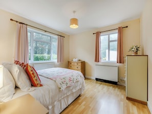 A bedroom with a bed, dresser, radiator, and windows.
