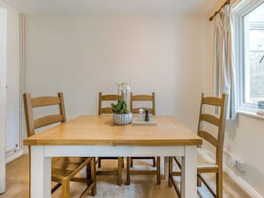 A dining table with chairs, a potted plant, and a chess set.