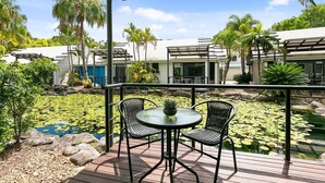 A covered outdoor area with a table and chairs, a small pond with lily pads, and palm trees. - Unit 46 - Resort Living, Luxury getaway, Close 2 Noosa River (Noosaville)