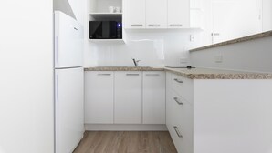 A modern kitchen with white cabinetry, a granite countertop, and a built-in microwave. - Unit 46 - Resort Living, Luxury getaway, Close 2 Noosa River (Noosaville)