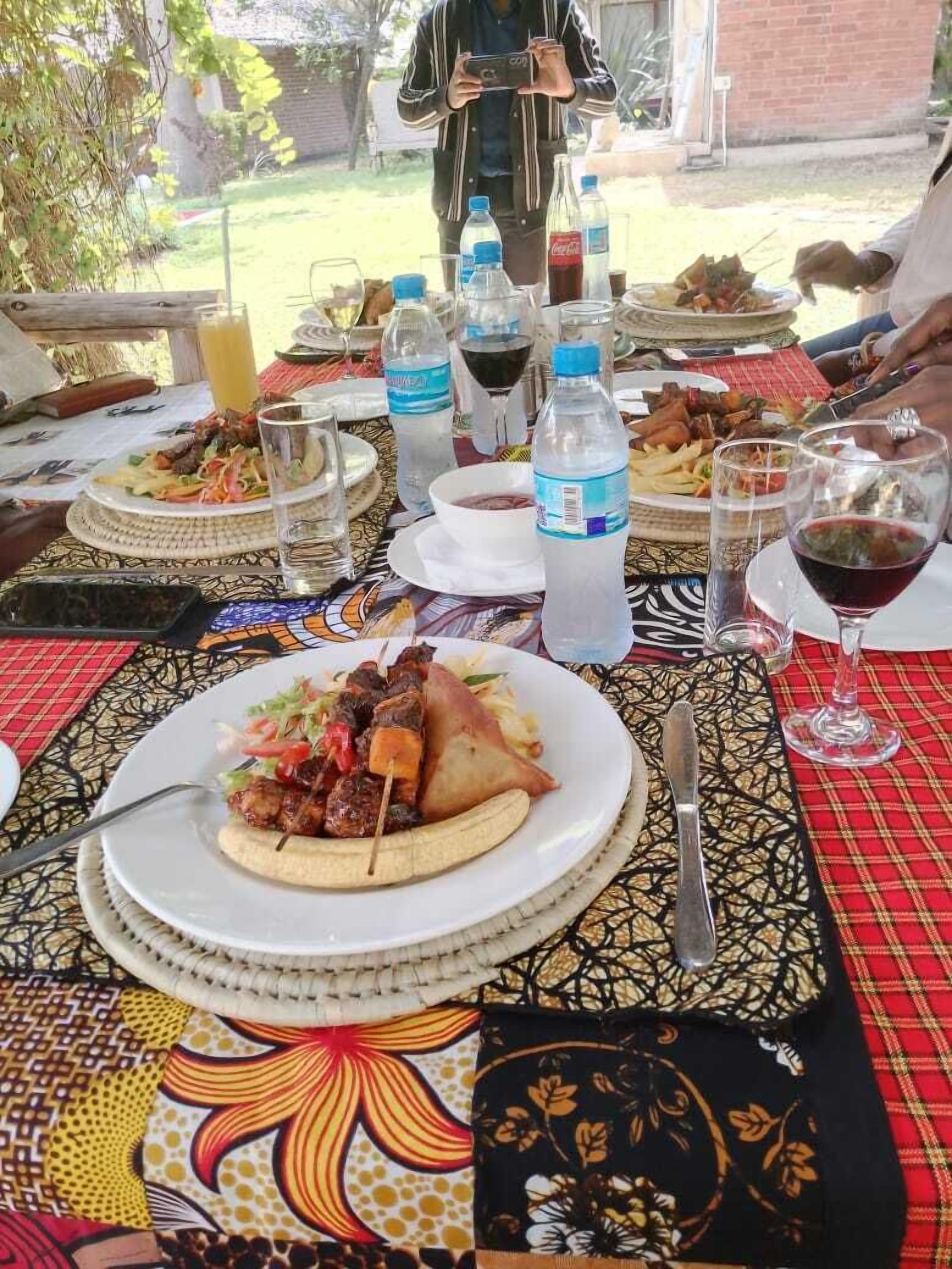 A dining table with various dishes, including skewers and a banana, and bottles of water and wine.