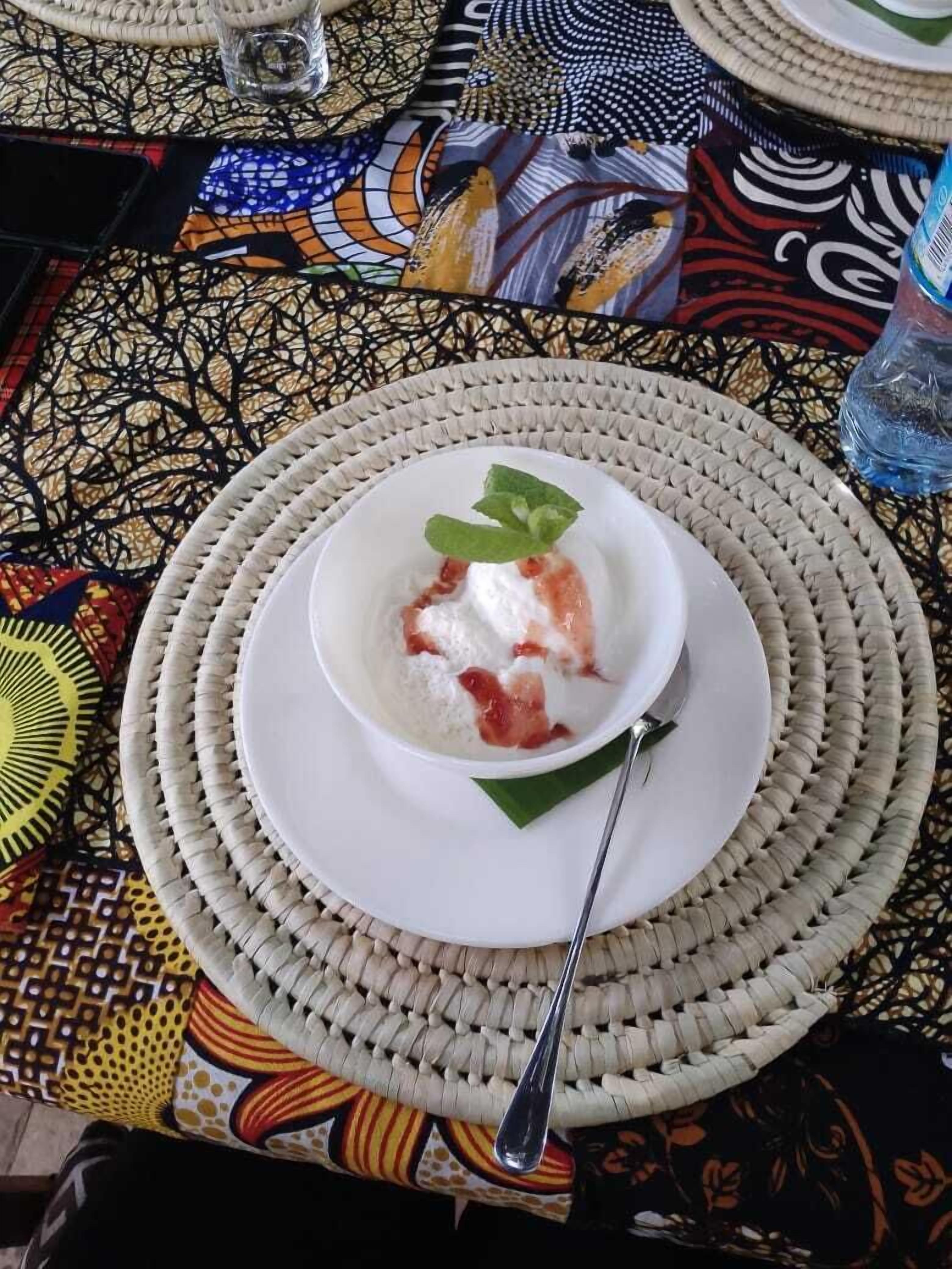 Uma tigela de comida com uma colher sobre um descanso de mesa trançado.