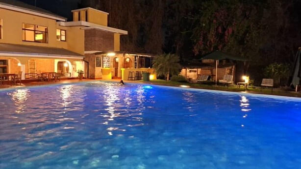 A swimming pool at night with a building in the background. - Ilboru Safari Lodge - The Platinum Route Company Limited (Arusha)