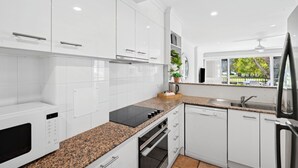 A modern kitchen with white cabinets, granite countertops, and a built-in oven.