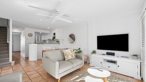 A modern living room with a grey sofa, a white entertainment unit, and a flat-screen TV.