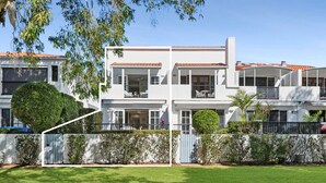 A two-story building with a white exterior, multiple balconies, and a well-maintained lawn.