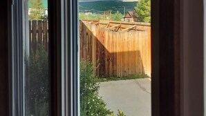 A view through a window, including a wooden fence, greenery, and distant mountains.