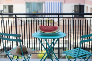 A balcony with a table holding a watermelon slice, two chairs, and a straw hat on one of the chairs. - Suite Positano - 100 meters from the beach (Maiori)