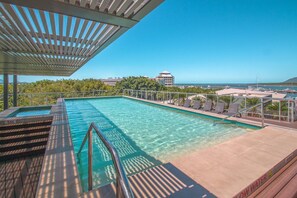Enjoy a refreshing swim in the pool surrounded by ocean views and comfortable seating.