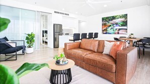 Un salon moderne avec un canapé en cuir, une table basse et un coin repas avec des chaises.