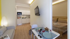 A compact hotel room with a kitchenette, a dining area, and a bed. - Suite Nerano - In the center of Maiori, a few steps from the sea (Maiori)