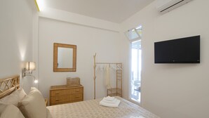 A bedroom with a bed, a wooden dresser, a mirror, a TV, and a window. - Suite Nerano - In the center of Maiori, a few steps from the sea (Maiori)