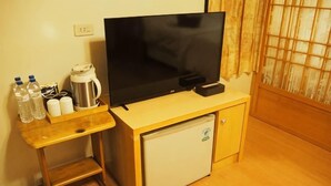 A small room with a wooden desk, a television, a mini fridge, and a window with curtains. - Shexia Li Yu (Pingtung)