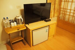 A small room with a wooden desk, a television, a mini fridge, and a window with curtains. - Shexia Li Yu (Pingtung)