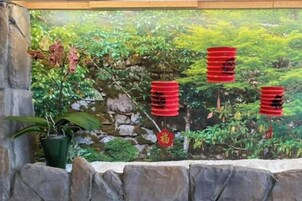 Un muro de piedra con un mural de vegetación y farolillos rojos.