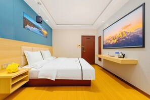 Une chambre d’hôtel avec un lit, une télévision, une étagère avec une bouilloire et une porte.