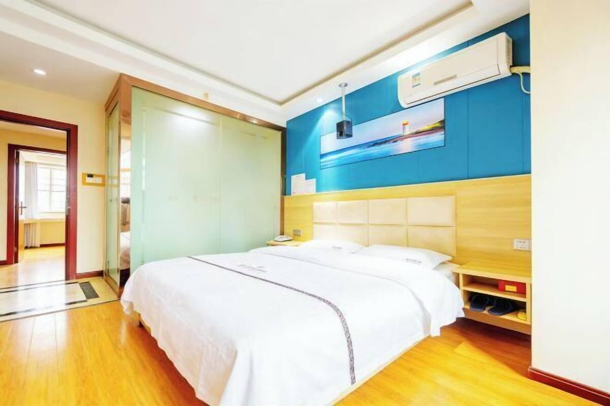 Ein Hotelzimmer mit einem großen Bett, einem Nachttisch, einer Wand-Klimaanlage und Blick ins Freie.