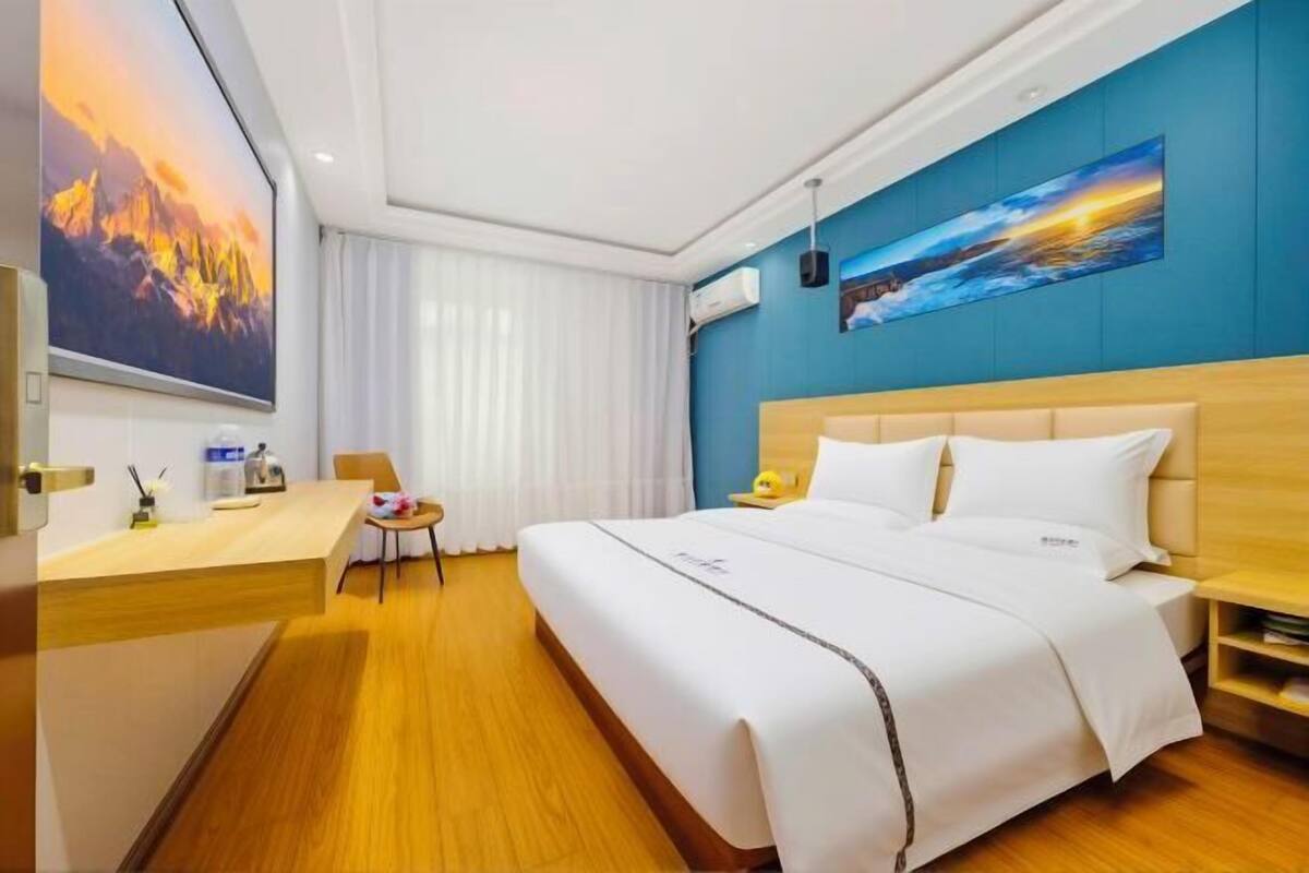 Ein Hotelzimmer mit Bett, Schreibtisch, Stuhl und Blick auf Berg und Meer.