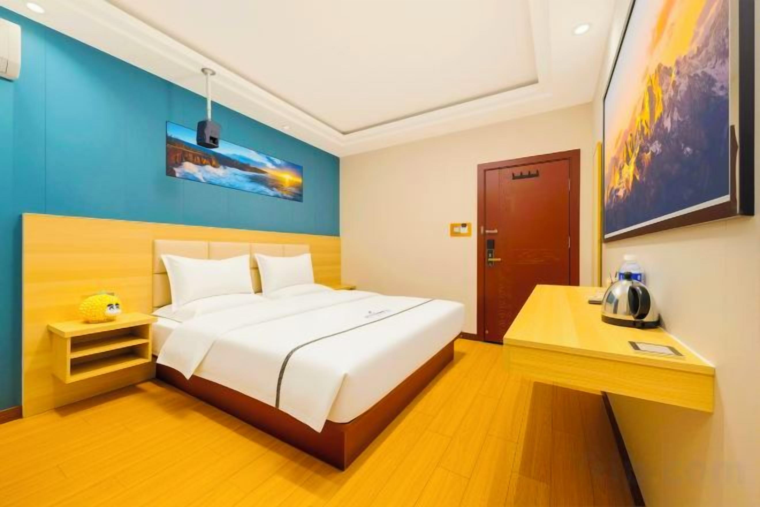 A hotel room with a bed, bedside table, and a desk with a chair.