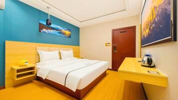 A hotel room with a bed, bedside table, and a desk with a chair.