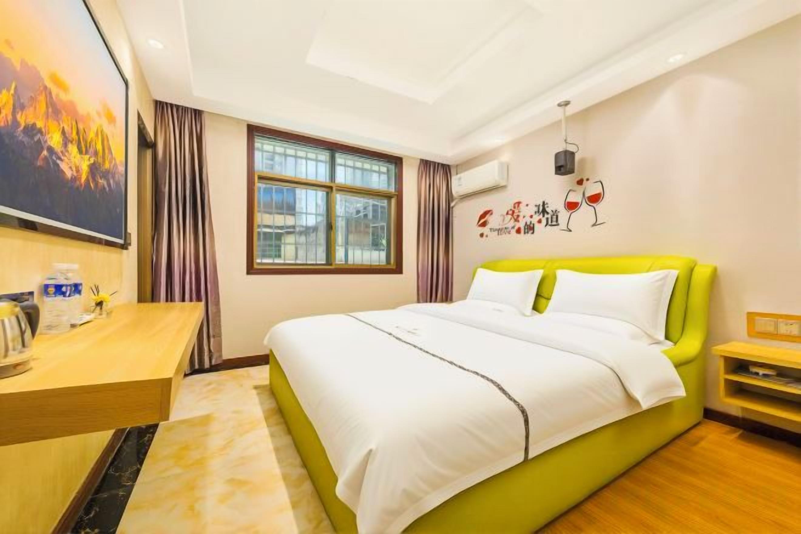 Habitación de hotel con una cama, un escritorio, un ventanal y un adorno en la pared.