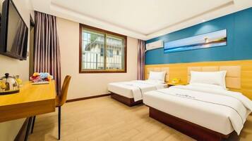A hotel room with two beds, a desk, a chair, a TV, and a window with curtains.
