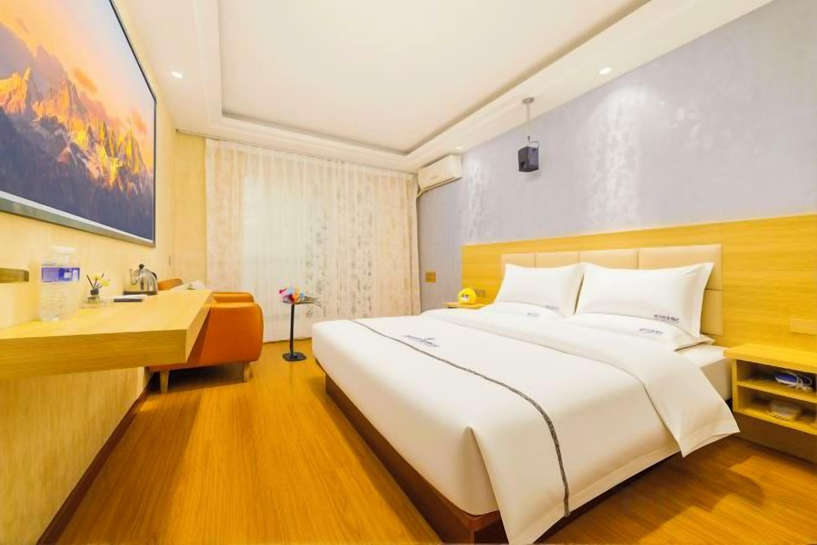 A hotel room with a bed, a desk, and a large window.