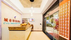 En hotellobby med en receptionsdisk, en väggmonterad TV och ett stort fönster med utsikt över gatan.