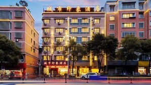 Ett hotell med flera våningar, ett iögonfallande skylt, flera balkonger och en väl upplyst fasad.