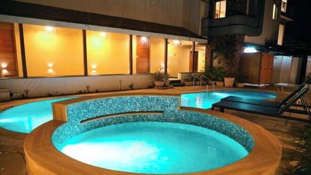 A hot tub area with a tiled edge, surrounded by lounge chairs and potted plants. - Rosetum Anjuna Goa (Anjuna)