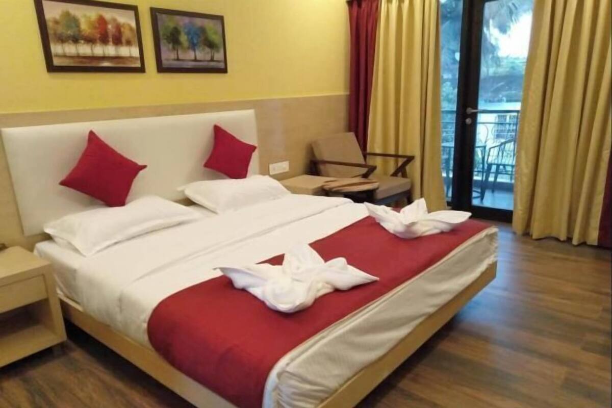 A hotel room with a bed, a nightstand, a chair, and a balcony view.