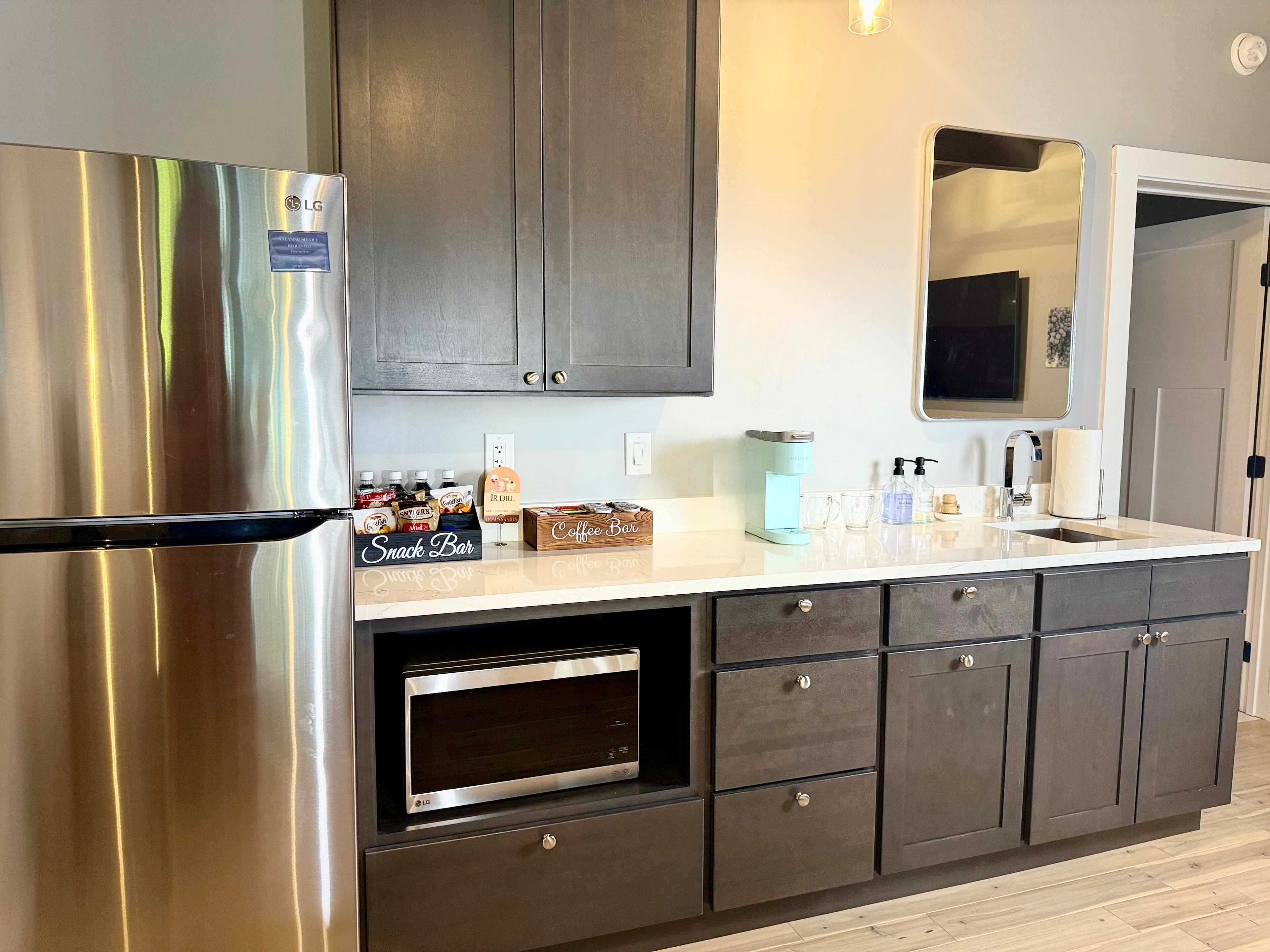 Una cocina moderna con un refrigerador de acero inoxidable, un horno empotrado y una barra para café.