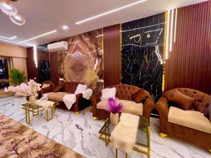 A modern lounge area with tufted sofas, a marble-patterned floor, and a decorative wall with a key and a lamp. - Nemes Pyramids View Inn (Giza)