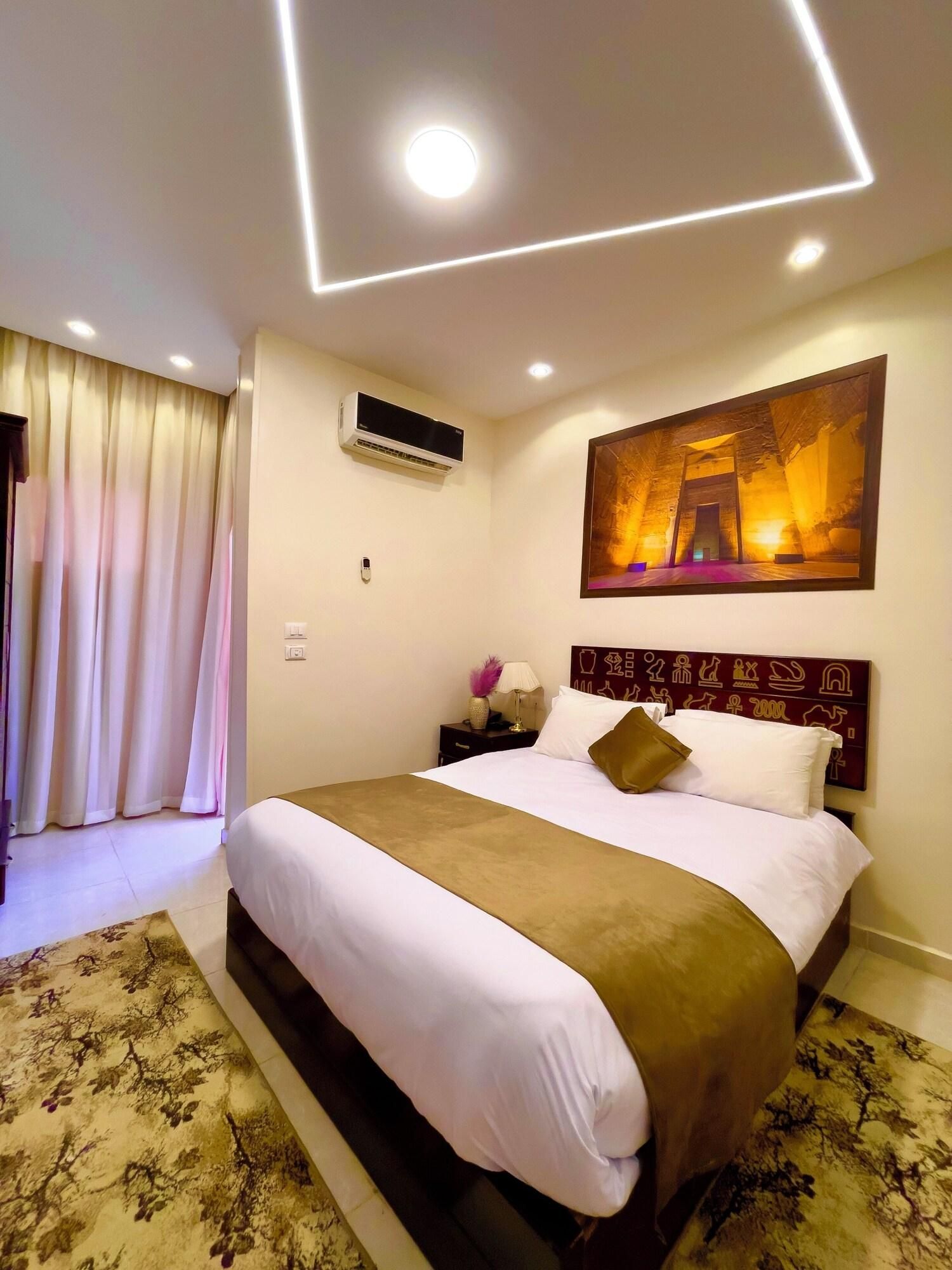 Une chambre d’hôtel avec un lit, une table de chevet, un appareil de climatisation, un tableau et un rideau.