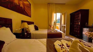 A hotel room with two beds, a nightstand, a lamp, a wardrobe, and a view of the outdoors. - Nemes Pyramids View Inn (Giza)