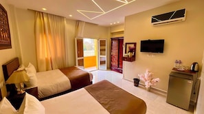 A hotel room with two beds, a television, a minibar, and a sliding door to a balcony. - Nemes Pyramids View Inn (Giza)